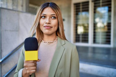 Sokakta mikrofon kullanan kendine güvenen genç Latin kadın.