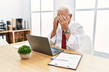 Ofiste çalışan son sınıf öğrencisi ağlarken yüzünü ellerle kapatan üzgün suratlı bir bilgisayar dizüstü bilgisayar kullanıyor. depresyon kavramı. 