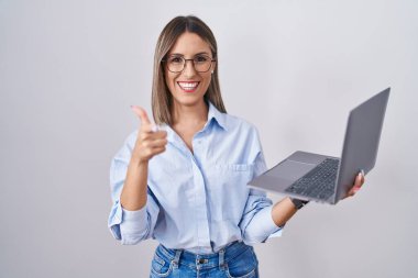 Young woman working using computer laptop pointing fingers to camera with happy and funny face. good energy and vibes. 