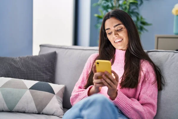 Jonge Spaanse Vrouw Met Behulp Van Smartphone Zitten Bank Thuis — Stockfoto