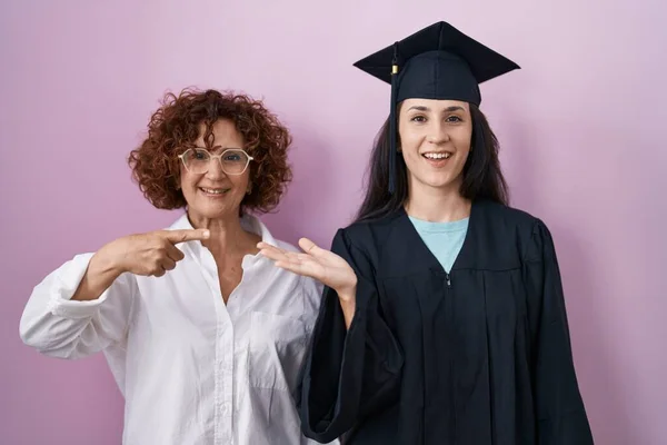 Hispanic Mor Datter Iført Graduering Cap Ceremoni Kåbe Forbløffet Smilende - Stock-foto