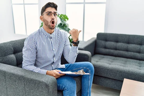 Young Psychologist Man Consultation Office Surprised Pointing Hand Finger Side — Stock fotografie