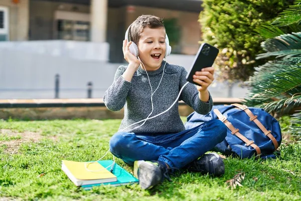 公園で音楽を聞いて自信を持って笑っているブロンドの子供の学生 — ストック写真