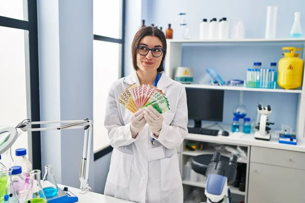 お金を持っている科学研究所で働いている若いヒスパニック系の女性側を見て笑って離れて考えを見つめ紙幣 — ストック写真