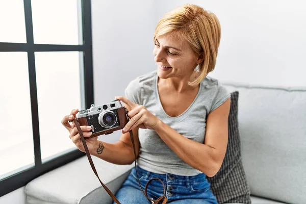 Middelbare Leeftijd Blonde Vrouw Glimlachen Zelfverzekerde Holding Vintage Camera Thuis — Stockfoto