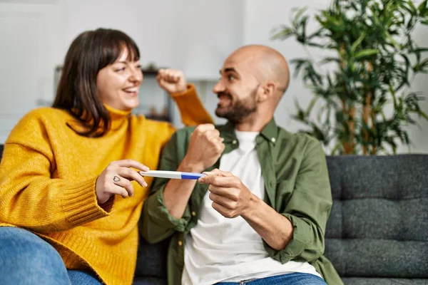 Young Hispanic Couple Smiling Happy Holding Pregnancy Test Sitting Sofa — Stockfoto