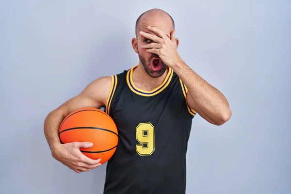 Young Bald Man Beard Wearing Basketball Uniform Holding Ball Peeking — Stock Photo, Image