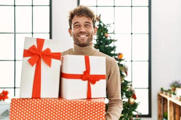 Jovem Hispânico Sorrindo Confiante Segurando Presentes Natal Casa — Fotografia de Stock