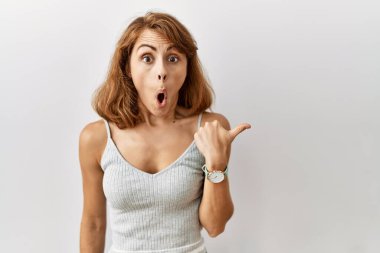 Güzel, beyaz bir kadın izole edilmiş arka planda duruyordu. Elle işaret ederek şaşırdı, ağzı açık şaşkın bir ifadeyle.. 