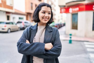 Young woman standing with arms crossed gesture looking to the side at street