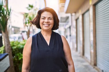 Güneşli bir günde mutlu ve kendinden emin gülümseyen orta yaşlı İspanyol kadın.