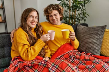 Kafkasyalı genç bir çift kahve içiyor ve evde birbirlerine sarılıyorlar.