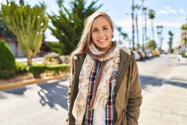 Sokakta kendine güvenen genç sarışın kadın gülümsüyor