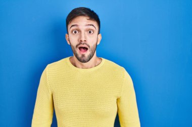 Mavi arka planda duran İspanyol adam şaşkınlık ve şaşkınlık dolu ifade, korku ve heyecan dolu yüz ifadesiyle dehşete düşmüş ve şok olmuştu.. 