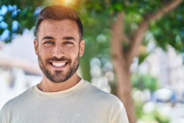 Parkta kendinden emin gülümseyen İspanyol genç adam.