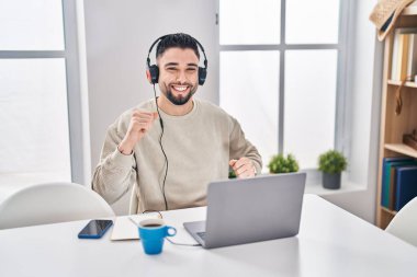 Genç Arap adam evde oturmuş müzik dinliyor.