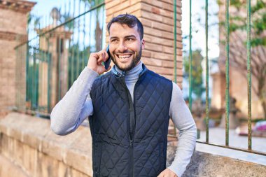 Genç İspanyol adam gülümsüyor. Kendine güveniyor. Sokakta akıllı telefondan konuşuyor.