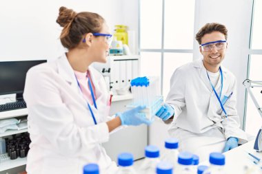 Man and woman wearing scientist uniform holding test tube at laboratory
