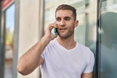 Kafkasyalı genç adam gülümsüyor. Kendine güvenen caddedeki akıllı telefondan konuşuyor.