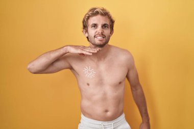 Caucasian man standing shirtless wearing sun screen cutting throat with hand as knife, threaten aggression with furious violence 