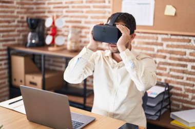 Genç iş adamı ofiste sanal gerçeklik gözlüğü kullanıyor.