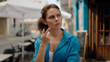 Sokakta şüpheli bir ifadeyle duran genç kadın.