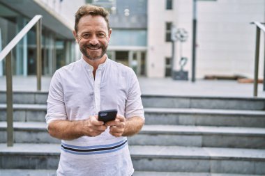 Şehirde akıllı telefon kullanan orta yaşlı bir adam.