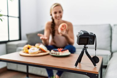 Beyaz bir kadın evdeki kanepede oturan şekerleri gösteren bir video görüşmesi yapıyor.