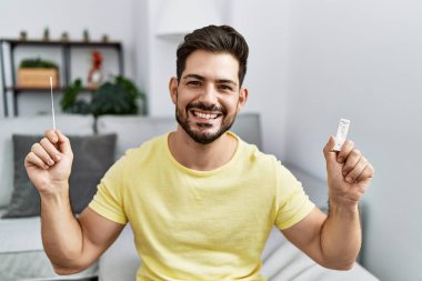 Young man with beard holding coronavirus infection nasal test smiling with a happy and cool smile on face. showing teeth. 