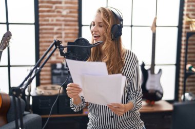 Müzik stüdyosunda şarkı söyleyen genç sarışın kadın.