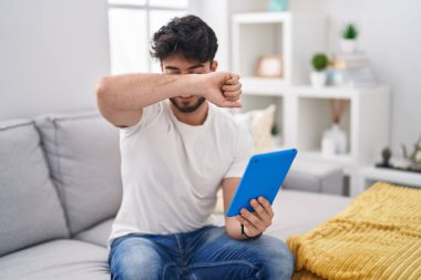 Dokunmatik ped kullanan İspanyol sakallı bir adam kanepeye oturmuş güler yüzle bön bön bakınıyor. Şaşırdım ve çıktım. 