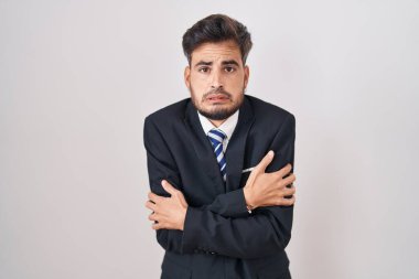 Dövmeli, takım elbiseli ve kravatlı genç İspanyol adam kış soğuğu için titriyor ve donuyor. Yüzünde üzgün ve şok ifadesi var. 