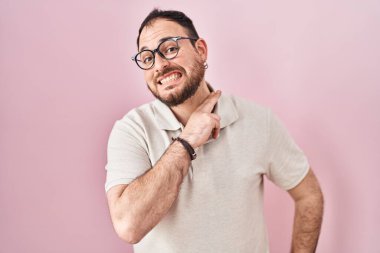 Plus size hispanic man with beard standing over pink background cutting throat with hand as knife, threaten aggression with furious violence 