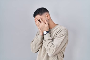 Genç yakışıklı adam izole edilmiş arka planda duruyor. Ağlarken yüzünü ellerle kapatan üzgün bir yüz ifadesi var. Depresyon kavramı. 
