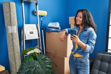 Young chinese woman smiling confident using smartphone at home