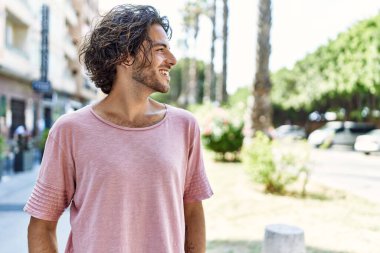 Genç İspanyol adam gülümsüyor. Mutlu bir şekilde şehrin caddesinde duruyor..