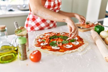 Genç, güzel İspanyol kadın mutfakta İtalyan pizzası hazırlıyor.