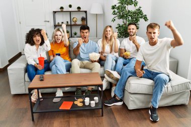 Bir grup insan evdeki kanepede oturmuş öfkeyle bağırıyor, öfkeyle bağırıyor ve el kaldırıyor. 