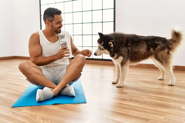 Young hispanic man smiling confident playing with dog at sport center