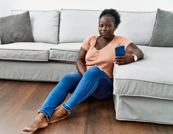 Νεαρή Αφρικανή Γυναίκα Που Χρησιμοποιεί Smartphone Κάθεται Στο Πάτωμα Στο — Φωτογραφία Αρχείου