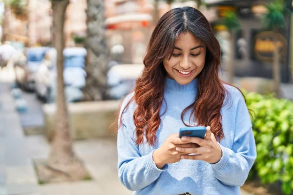 Sokakta akıllı telefon kullanan, kendine güvenen genç İspanyol kadın.