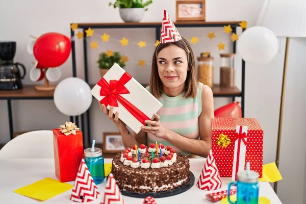 Latynoska Kobieta Świętuje Urodziny Tortem Trzymając Prezent Uśmiechnięta Patrząc Bok — Zdjęcie stockowe