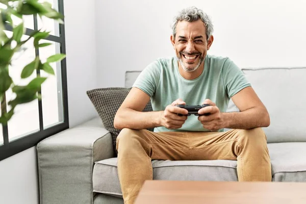 中年时 他的惊慌失措的男人坐在沙发上玩电子游戏 面带微笑 面带微笑 面带微笑 — 图库照片
