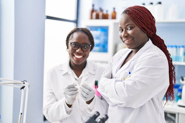 アフリカ系アメリカ人女性科学者が腕を組んで立っているサンプルを見ると — ストック写真