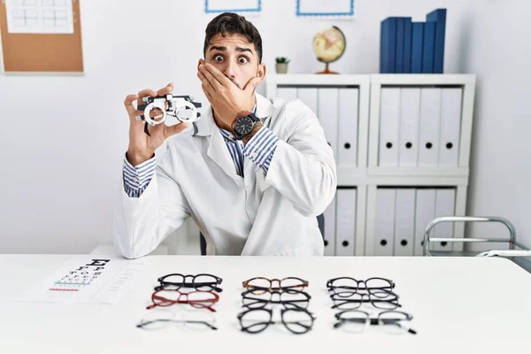 Young Optician Man Holding Optometry Glasses Shocked Covering Mouth Hands — 图库照片