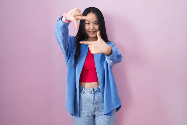 Young Asian Woman Standing Pink Background Smiling Making Frame Hands — Foto Stock