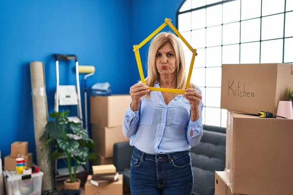 Middle Age Blonde Woman Moving New Home Puffing Cheeks Funny — Stockfoto
