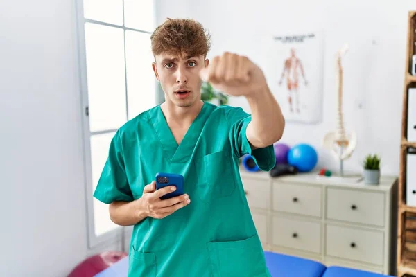 Young Caucasian Physio Man Using Smartphone Medical Clinic Annoyed Frustrated — Stockfoto