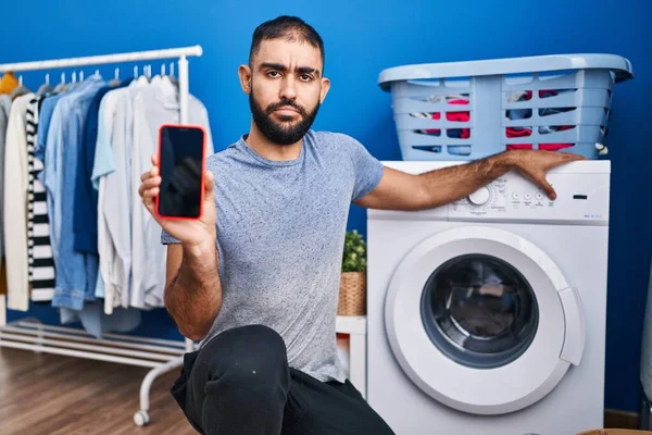 Middle East Man Beard Showing Smartphone Screen Washing Machine Skeptic — Stockfoto