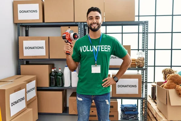 Hombre Árabe Joven Vistiendo Uniforme Voluntario Sosteniendo Cinta Embalaje Centro — Foto de Stock